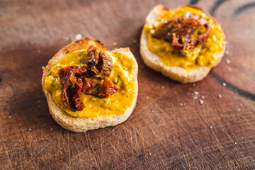 simple food ingredients, bread slices with sweet potoato and kale dip topped with sundried tomatoes