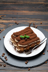 Classic tiramisu dessert on ceramic plate on wooden background
