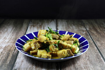 Traditional fried and stirred cutting belly pork with chilly, basil and seasoning with turmeric powder on the plate. Famous hot and spicy pork menu in Asia restaurant. 