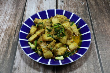 Traditional fried and stirred cutting belly pork with chilly, basil and seasoning with turmeric powder on the plate. Famous hot and spicy pork menu in Asia restaurant. 