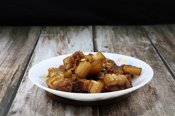 Traditional fried and stirred cutting belly pork with garlic, pepper, soy sauce and oyster sauce in Chinese style on the plate. Famous ancient appetizer menu in Asia restaurant. 