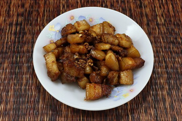 Traditional fried and stirred cutting belly pork with garlic, pepper, soy sauce and oyster sauce in Chinese style on the plate. Famous ancient appetizer menu in Asia restaurant. 
