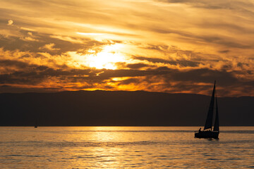 Couché de soleil sur le lac Léman avec bateau à voile en silhouette