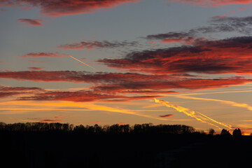 Ciel de soleil couchant avec nuages colorés et traces d'avion