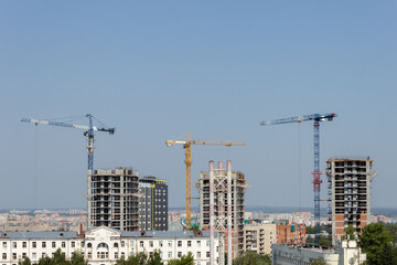 Construction cranes are building new modern skyscrapers. Active urban development with high-rise buildings