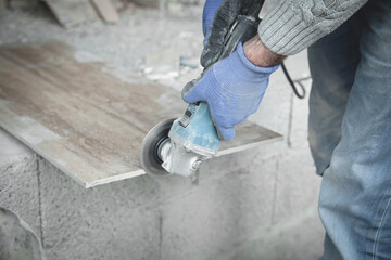 Worker cutting a tile with a grinder.
