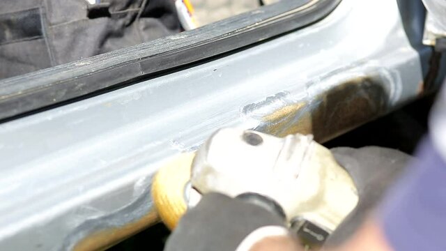 car repair and painting, a man removes rust from the car body using a sander