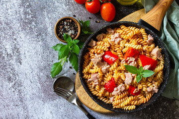 Healthy lunch. Fusilli pasta with canned tuna, grilled red peppers and tomatoes in frying pan on a stone countertop. Copy space.