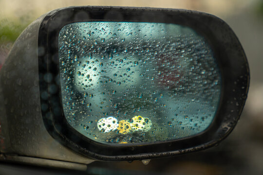 Raindrop outside the car in raining day. Raindrops on car window and rear view mirror. wing mirror. Morning dew drops on a car side mirror passenger side for raint seaon concept