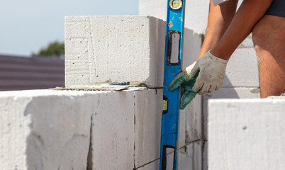 A worker builds the walls of a house from aerated concrete bricks.