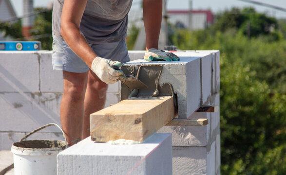 A worker builds the walls of a house from aerated concrete bricks.