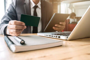 Male businessman use credit cards to conduct financial transactions through phones, tablet, and...