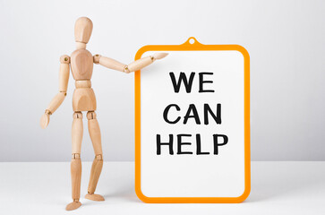 Wooden man shows with a hand to white board with text We can help