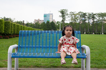 Fototapeta na wymiar A little girl alone on a blue bench