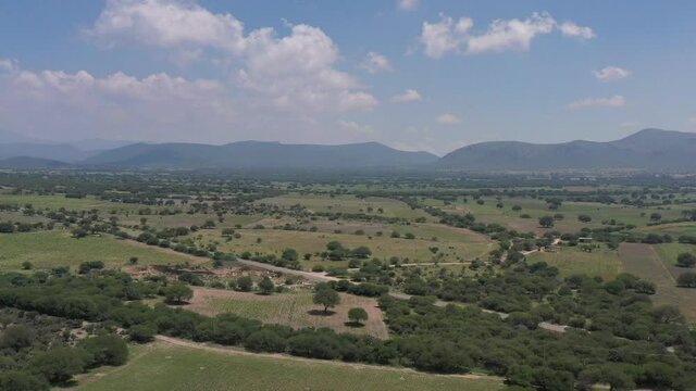 Vista a&eacute;rea lateral del Valle del Marqu&eacute;s, regi&oacute;n vitivin&iacute;cola en el Estado de Quer&eacute;taro, con unas monta&ntilde;as y cielo azul como fondo.