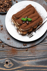 Classic tiramisu dessert on ceramic plate on wooden background