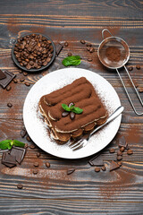 Classic tiramisu dessert on ceramic plate on wooden background