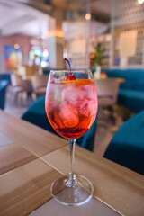 A glass with the red citrus cocktail. Alcohol summer beverage in a wine glass. Refreshing drink with ice.