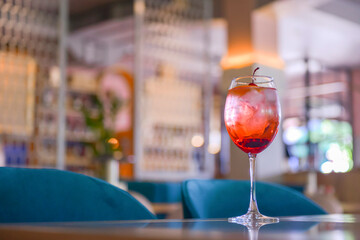 A glass with the red citrus cocktail. Alcohol summer beverage in a wine glass. Refreshing drink with ice.