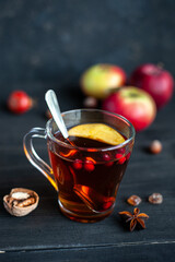 Autumn warming tea with berries and apples on a black wooden background. 