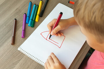 A small child draws a house with markers in the album. Step-by-step instructions