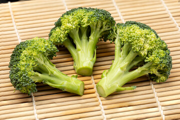 Fresh broccoli with drops of water isolated on bamboo mat background