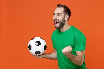 Happy man football fan in green t-shirt cheer up support favorite team with soccer ball clenching...