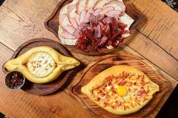 Georgian cuisine foodset from khachapuri and different kinds of meat on rusitc wooden table, flat lay, top view.