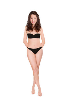 Full length portrait of an attractive cheerful woman wearing black bra and panties, studio photo isolated in front of white background