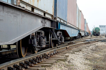 Obraz premium Freight cars with a wheelset node close-up going into the distance with the tanks of another train in the distance.