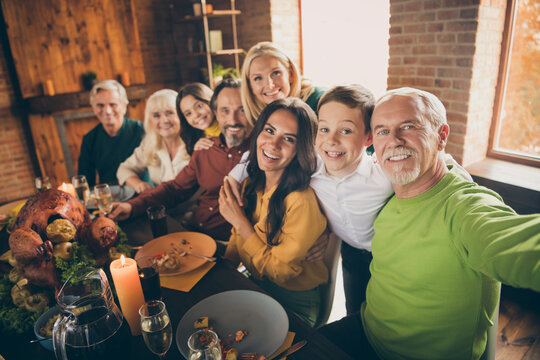 Self-portrait of nice cheery big full family brother sister grandparents grandson granddaughter sitting around served festal table embracing reunion at modern loft industrial brick interior house