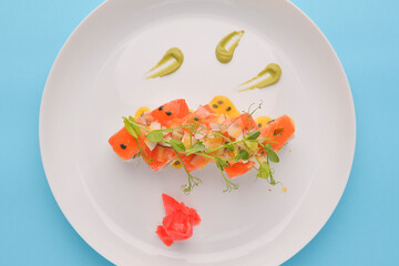 White rice sushi set with salmon fish and chia seeds served on a big white plate with ginger and wasabi sauce.