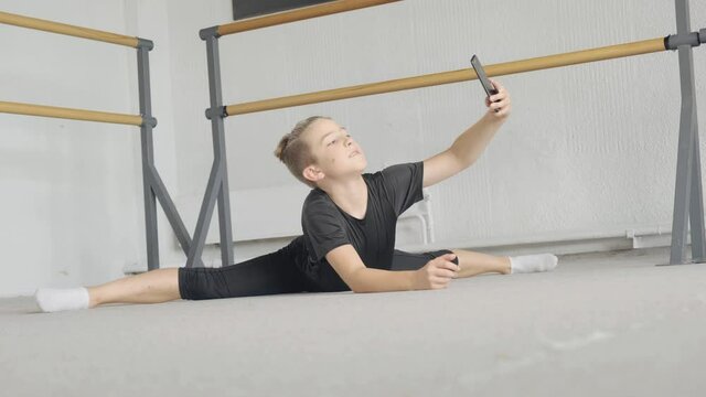 A handsome young guy is engaged in yoga, standing in the asana pose twine, and takes a selfie. The concept of sports and meditation. Stretching and yoga workout