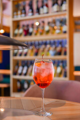 A glass with the red citrus cocktail. Alcohol summer beverage in a wine glass. Refreshing drink with ice.