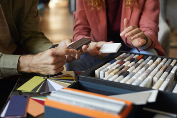 Close-up of designers sitting at the table and examining the pattern of tile they choosing the color in team