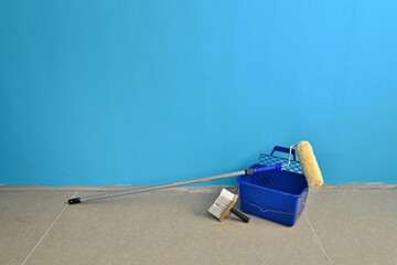 Painting equipment, brush, roller, bucket and paints near the blue wall. Ready to paint. Painting a children's room.