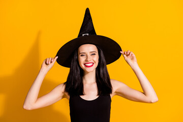 Photo of pretty charming young magician lady toothy beaming smile hold cap role play october event evening wear black wizard headwear dress isolated bright yellow color background