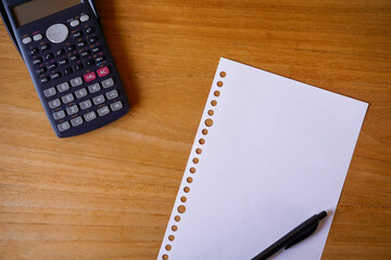 blank paper, ballpoint, and calculator for mockup concept on wooden board. finance, education background