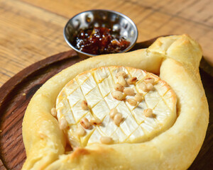 Khachapuri with brie cheese served on a wooden board. Traditional meal, Georgian cuisine concept