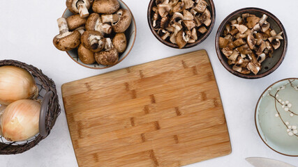Fresh raw organic brown mushrooms and yellow onion close up on kitchen table. Cooking process, ingredients, vegetarian recipe