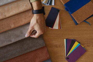 Close-up of fashion designer examining the colored fabric patterns at the table