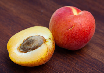 Naklejka na ściany i meble Closeup of whole and halved ripe apricots on wooden background. Harvest time
