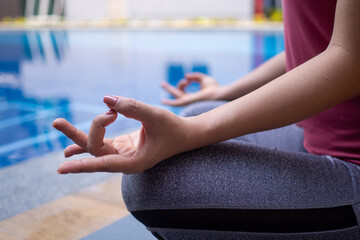Women calmly meditate by the pool. Woman doing yoga pose practicing peace of mind. yoga concept