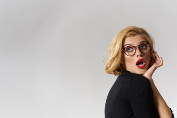 Blonde girl with glasses red lips black blouse cropped view glamor light background studio