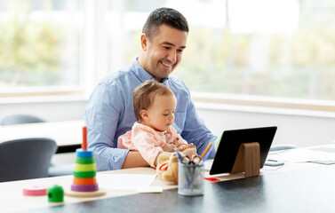 remote job, multi-tasking and family concept - middle-aged father with baby and tablet computer working at home office