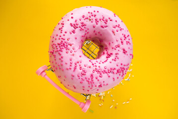 sweet pink donut in a shopping cart on a yellow background.