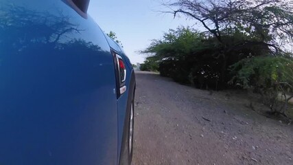 Shot of vehicle on dusty road heading towards the sea.
