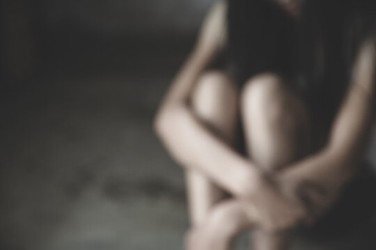  Blurred image of Young  women sitting in dark room feeling pain with life problem.   Stop violence against and sexual abuse women, domestic violence, human trafficking.