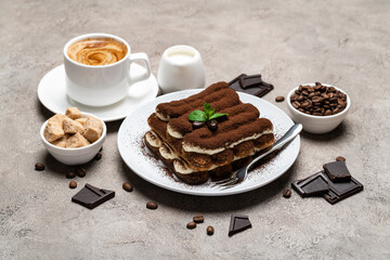 Classic tiramisu dessert, cup of coffee, sugar and milk on concrete background