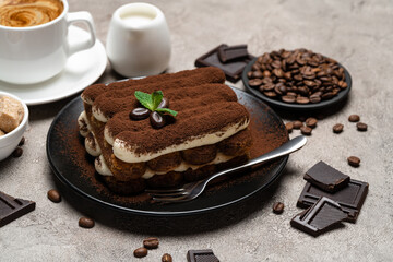 Classic tiramisu dessert, cup of coffee, sugar and milk on concrete background